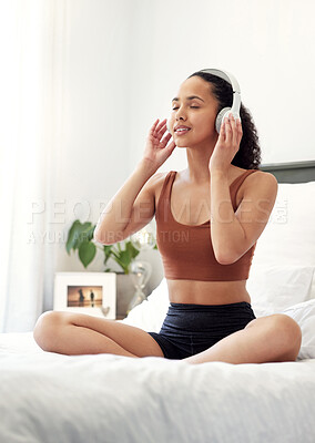 Buy stock photo Shot of a young woman listening to music while sitting on her bed at home