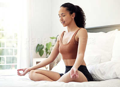 Buy stock photo Shot of a young woman meditating while sitting on her bed at home