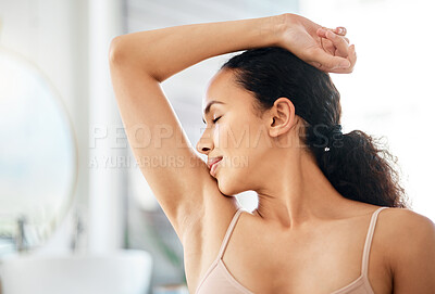 Buy stock photo Shot of a young woman smelling her underarm in a bathroom at home