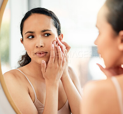 Buy stock photo Shot of a young woman popping a pimple on her face in the bathroom at home