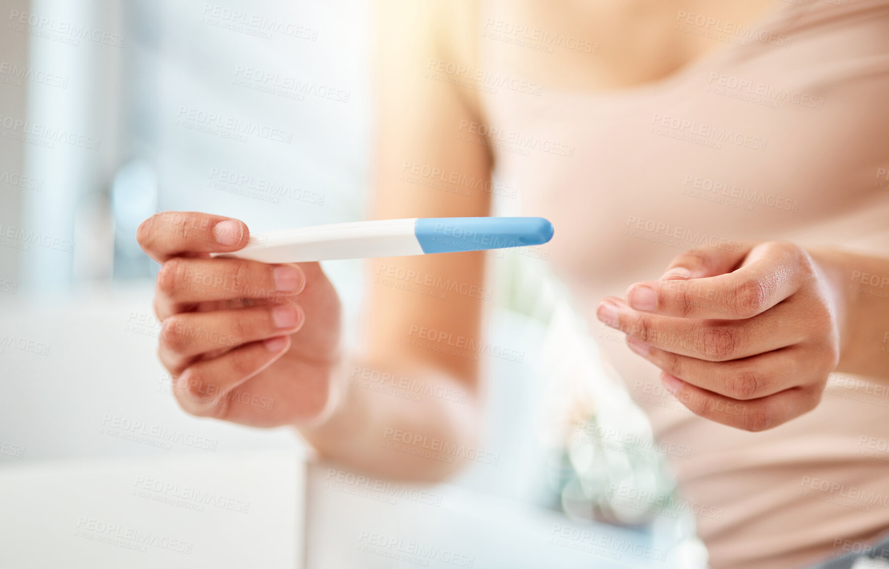 Buy stock photo Shot of an unrecognizable woman holding a pregnancy test at home