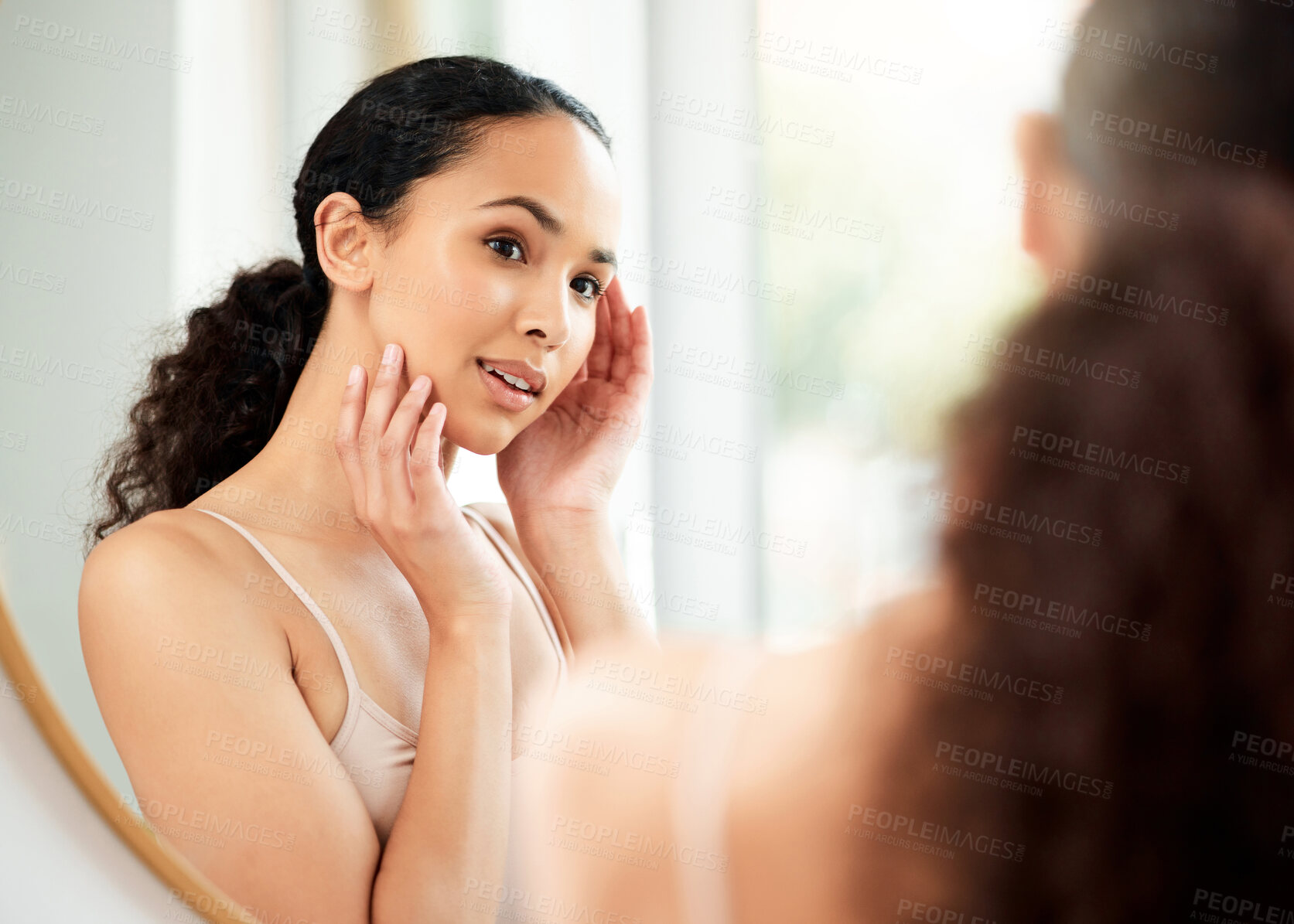 Buy stock photo Shot of a young woman admiring her skin in a bathroom at home