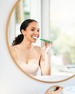 Buy stock photo Shot of a young woman brushing her teeth at home