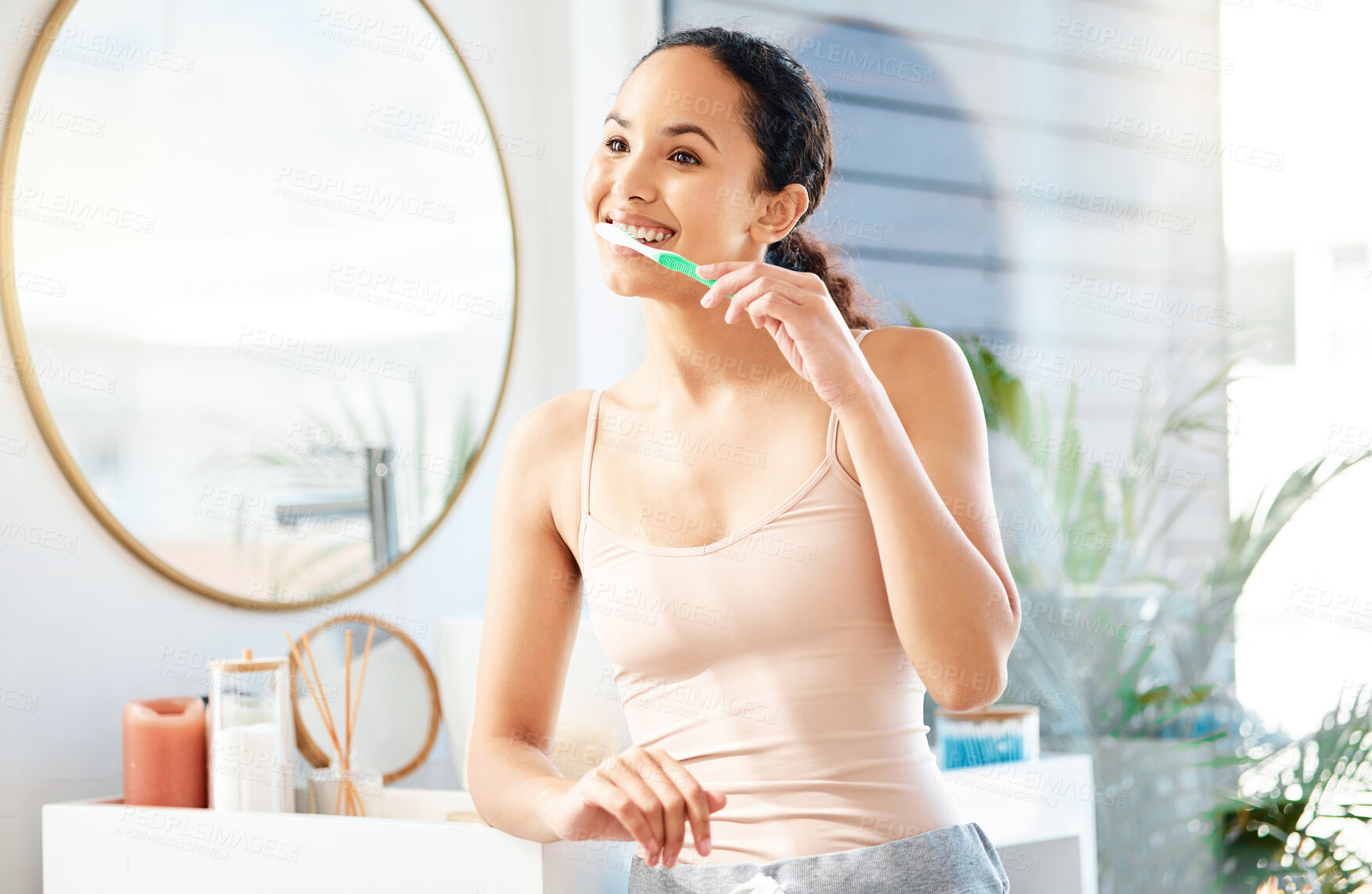 Buy stock photo Shot of a young woman brushing her teeth at home