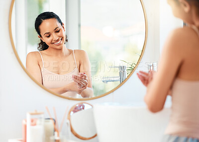 Buy stock photo Shot of a young woman applying cream to her hands at home