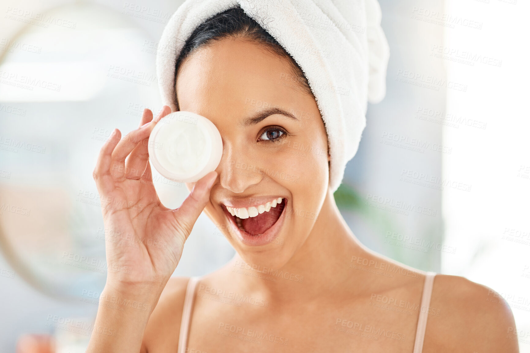 Buy stock photo Shot of a young woman applying cream to her face at home