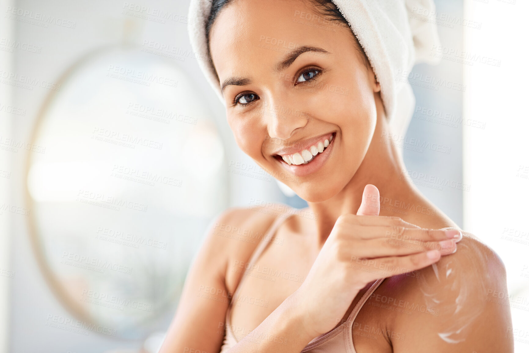 Buy stock photo Shot of a young woman applying cream at home