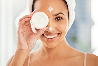 Buy stock photo Shot of a young woman applying cream to her face at home