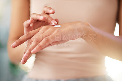 Buy stock photo Shot of an unrecognizable woman using cream at home