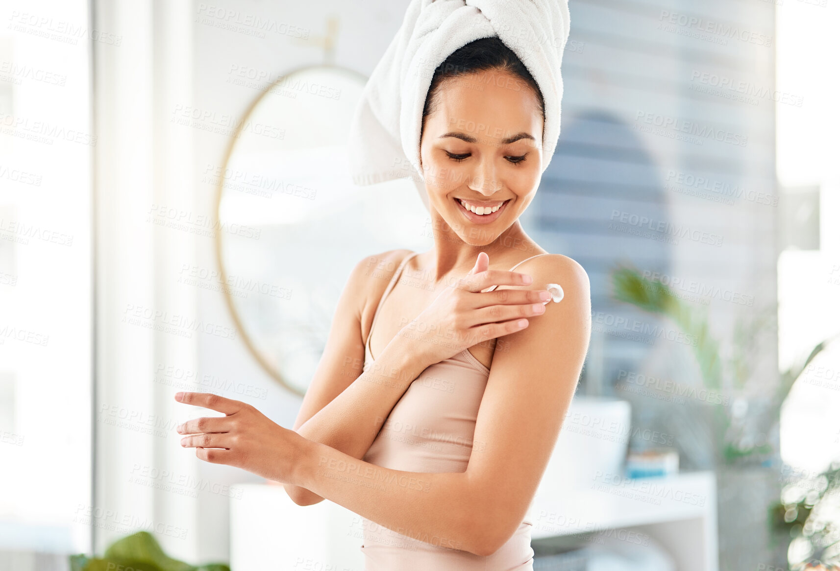 Buy stock photo Shot of a young woman applying cream at home