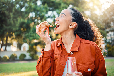Buy stock photo Shot of a young woman eating pizza in a park