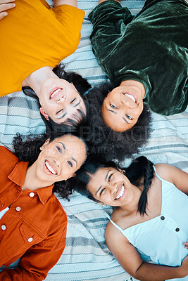 Buy stock photo Shot of female friends lying together on the blanket in a park