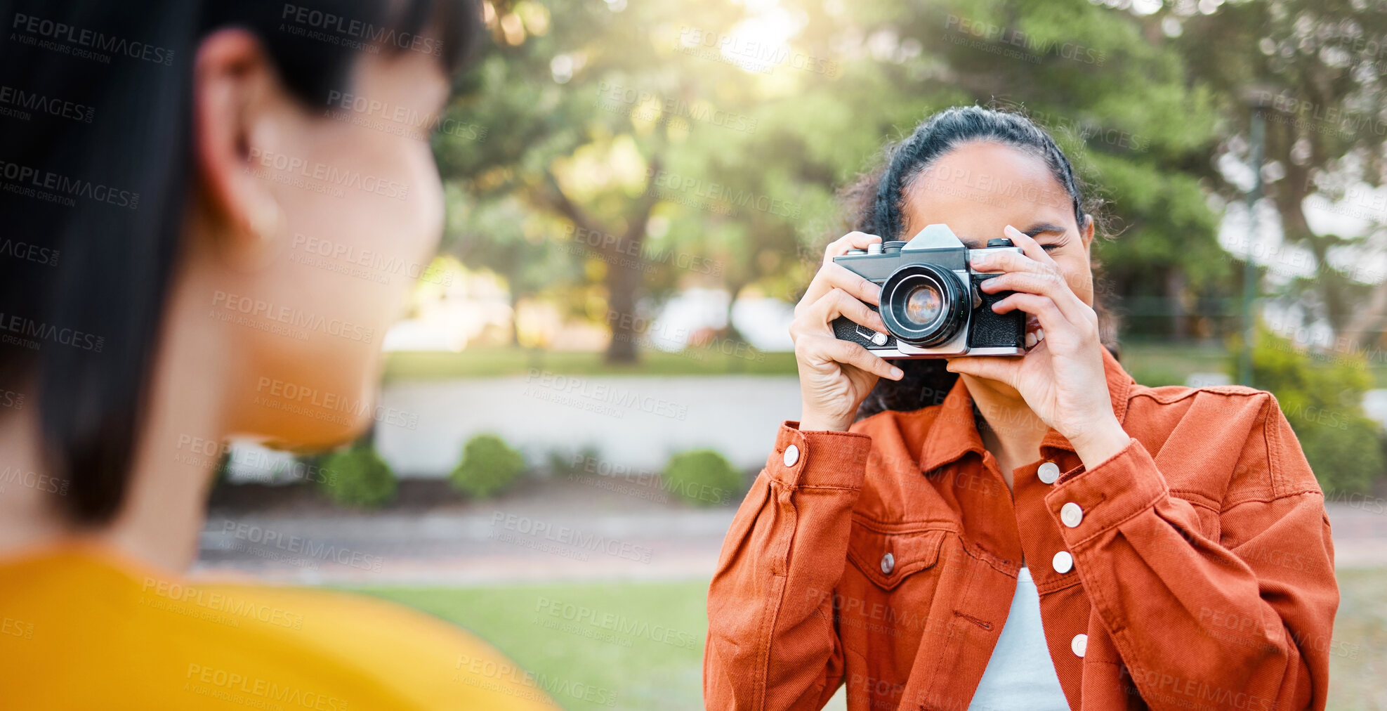 Buy stock photo Shot of a female taking photos of her friend outside