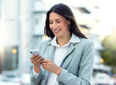 Buy stock photo Shot of a young businesswoman using a smartphone against an urban background