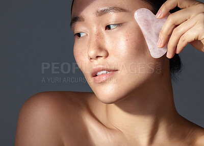 Buy stock photo Studio shot of a beautiful young woman using a scraping tool on her face