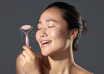 Buy stock photo Studio shot of a beautiful young woman holding a face roller
