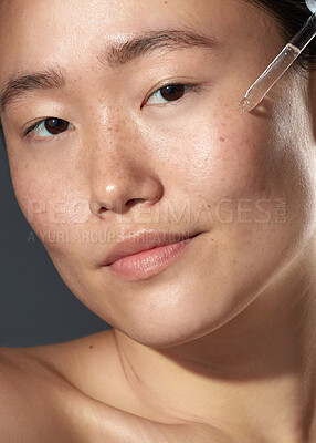 Buy stock photo Studio shot of a beautiful young woman using a face serum