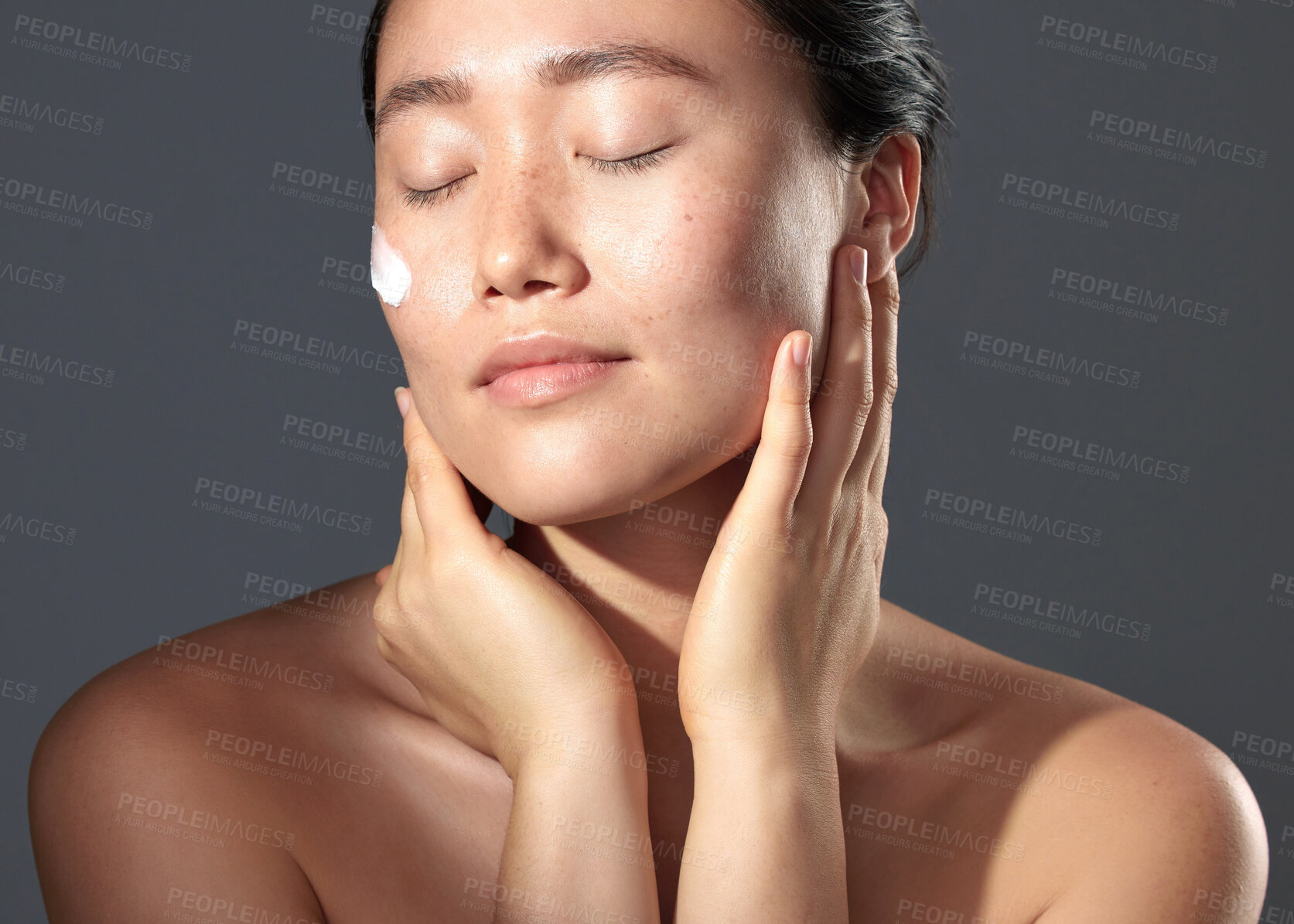Buy stock photo Studio shot of a beautiful young woman posing with moisturiser on her face