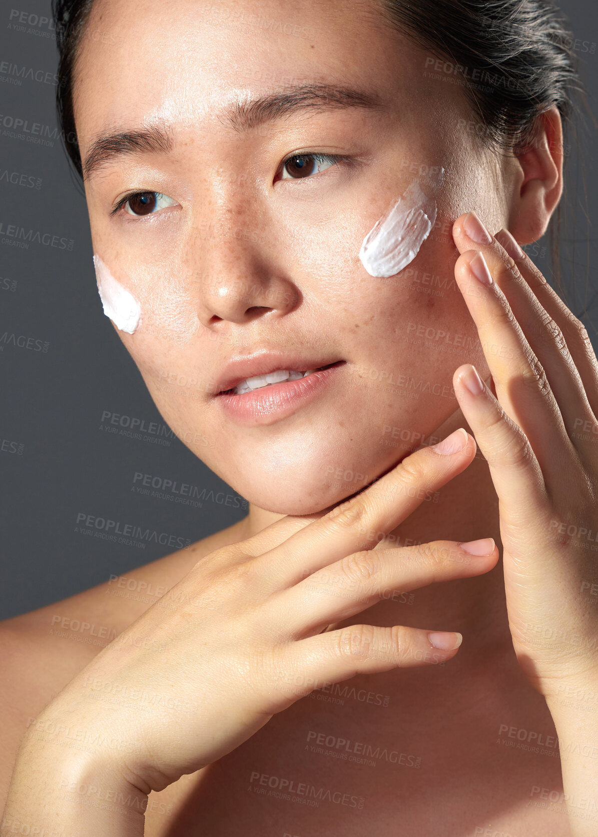 Buy stock photo Studio shot of a beautiful young woman posing with moisturiser on her face