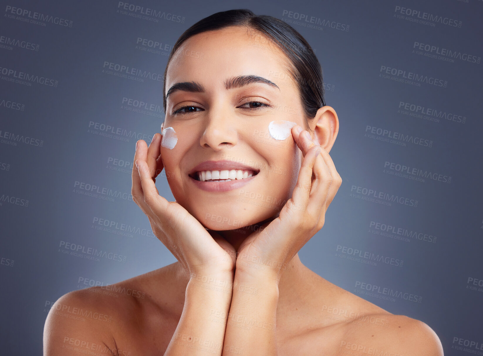 Buy stock photo Studio shot of a beautiful young woman applying a face cream