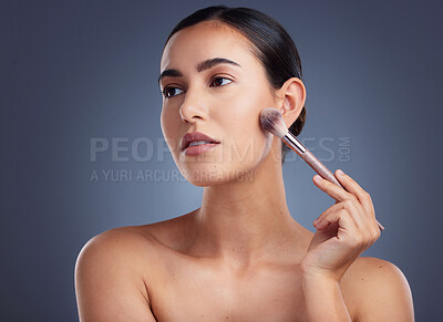 Buy stock photo Studio shot of a beautiful woman using a make-up brush on her cheek