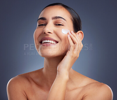 Buy stock photo Studio shot of a beautiful young woman applying a face cream