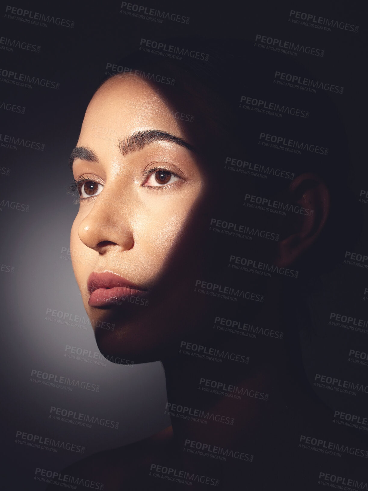 Buy stock photo Studio shot of a beautiful young woman posing with light beam against her face