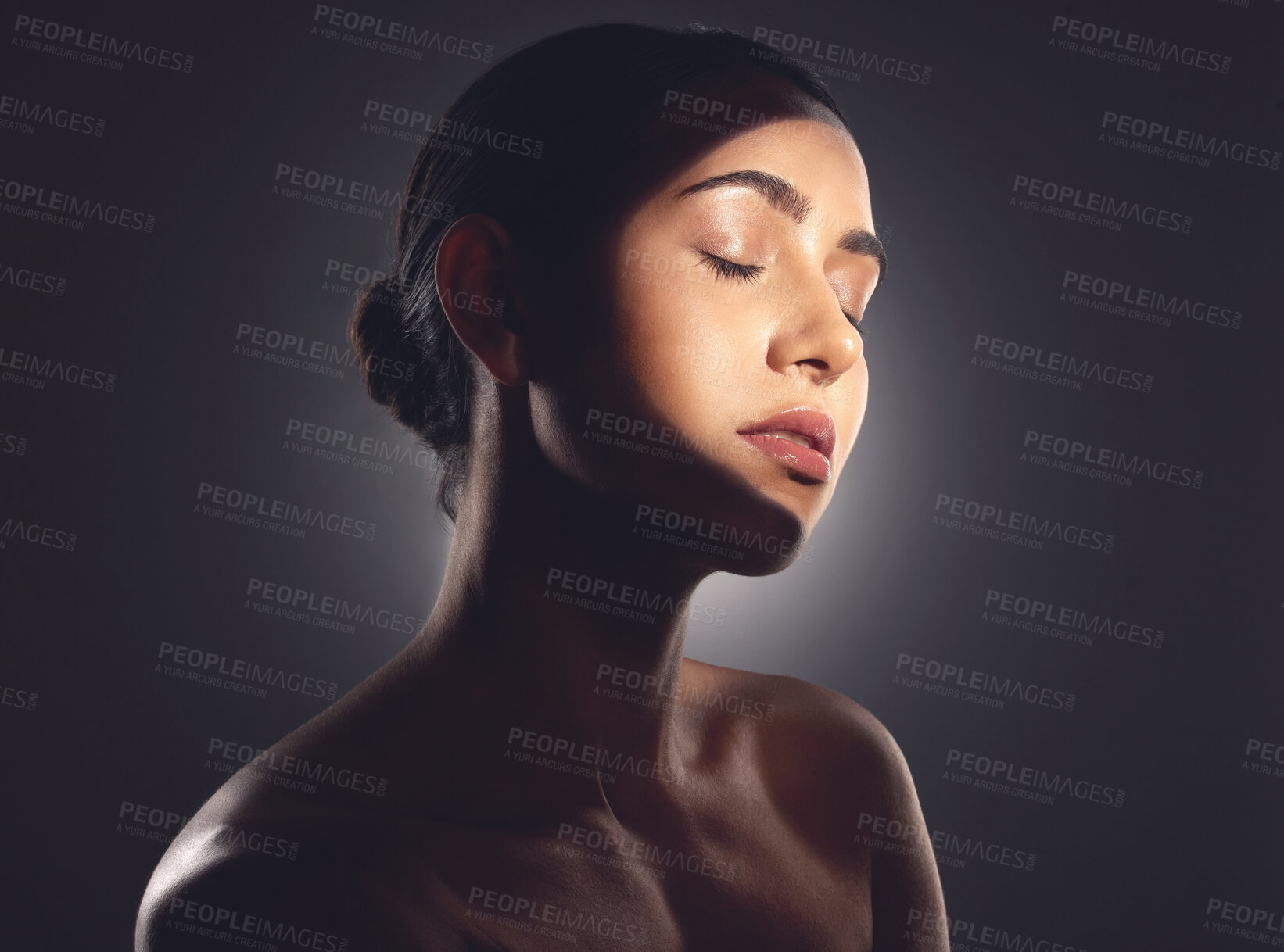 Buy stock photo Studio shot of a beautiful young woman posing with light beam against her face