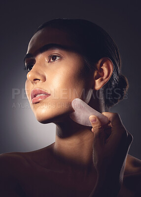 Buy stock photo Studio shot of a woman using a face scraping tool on her face