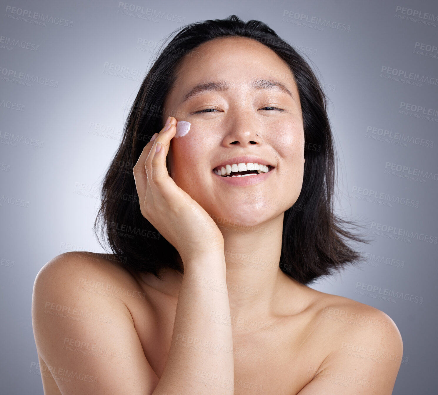 Buy stock photo Portrait, Asian woman and skincare with cream in studio for patch test, healthy skin and hydration. Smile, person or lotion for collagen benefits, facial moisturiser and self care on gray background