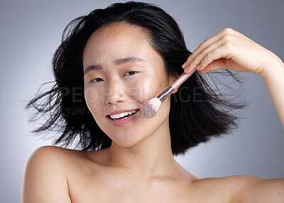 Buy stock photo Shot of a young woman applying makeup against a grey background