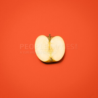 Buy stock photo Above, half apple and cut in studio for nutrition, healthy eating and gut health. Fresh fruit, divided or open on red background for fiber, digestion aid or antioxidants in diet with food for sharing