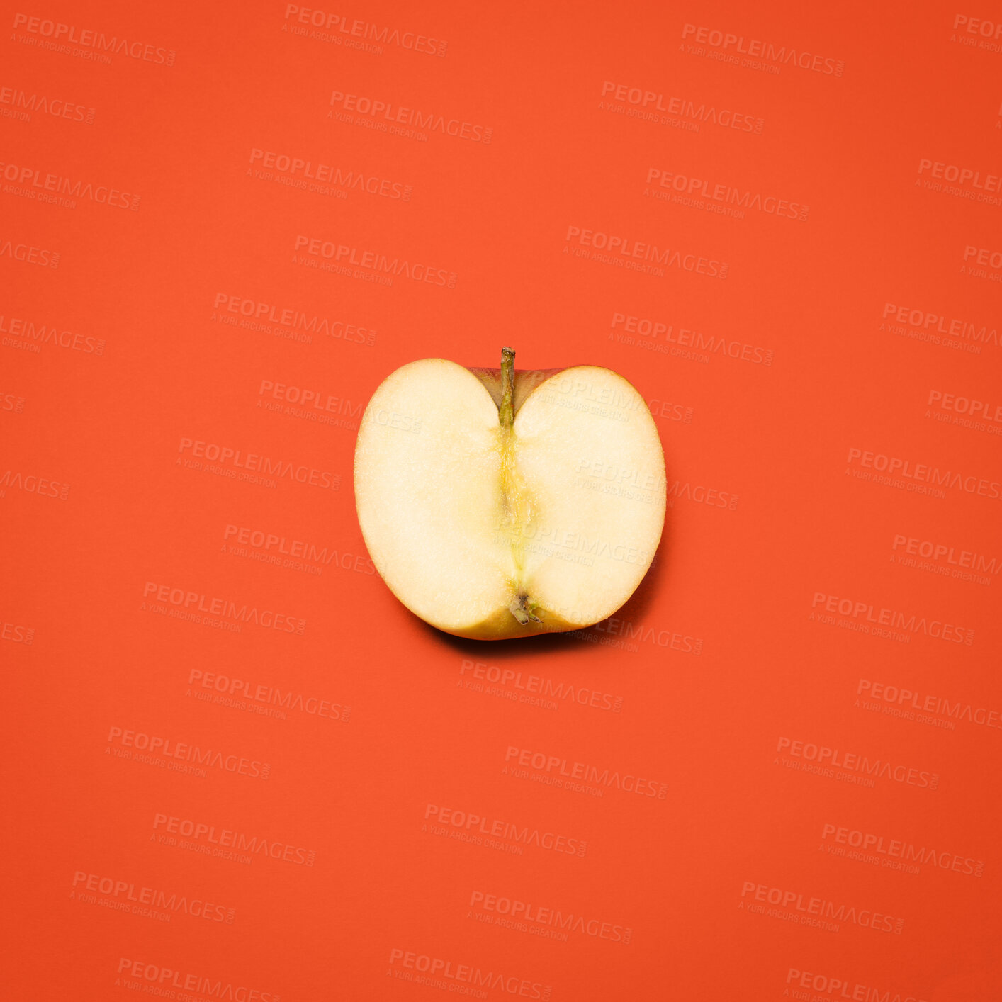 Buy stock photo Above, half apple and cut in studio for nutrition, healthy eating and gut health. Fresh fruit, divided or open on red background for fiber, digestion aid or antioxidants in diet with food for sharing