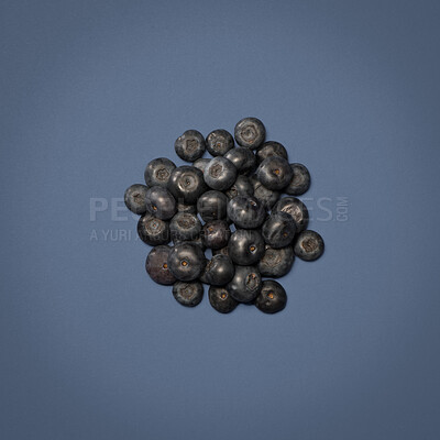 Buy stock photo Blueberry, pile and fruit in studio for diet or wellness, sustainability and organic snack for nutrition. Billberry, isolated and blue background for vitality or digestion, vitamins and fiber.