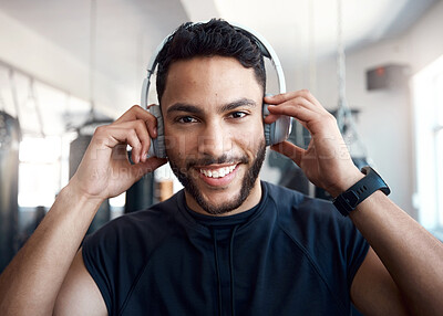 Buy stock photo Portrait of a sporty young man listening to music while exercising in a gym