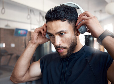 Buy stock photo Shot of a sporty young man listening to music while exercising in a gym