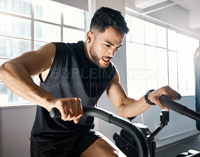 Buy stock photo Shot of a sporty young man working out on an exercise bike in a gym