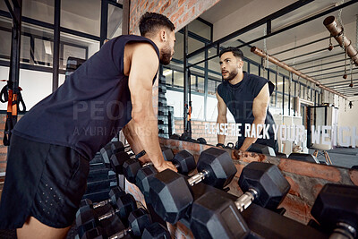 Buy stock photo Shot of a sporty young man looking at himself in a mirror while exercising in a gym