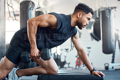 Buy stock photo Shot of a sporty young man exercising with a dumbbell in a gym