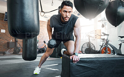 Buy stock photo Shot of a sporty young man exercising with a dumbbell in a gym