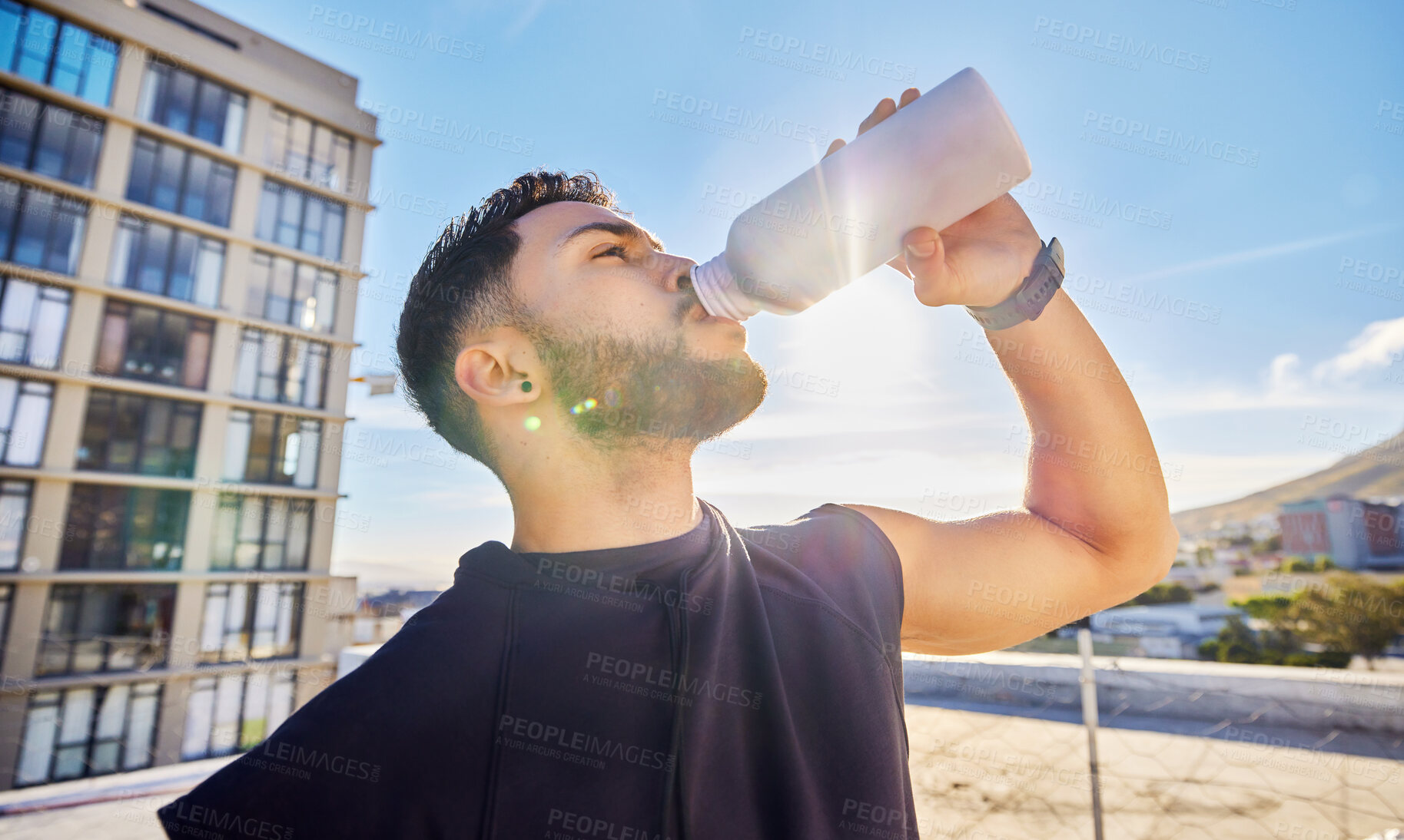 Buy stock photo Shot of a man drinking from a bottle while out for a workout