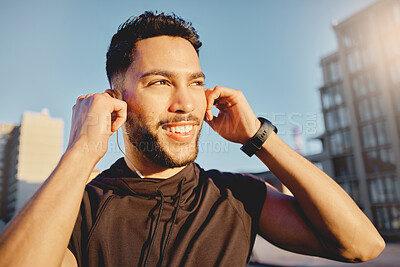 Buy stock photo Shot of a sporty young man wearing earphones while exercising outside