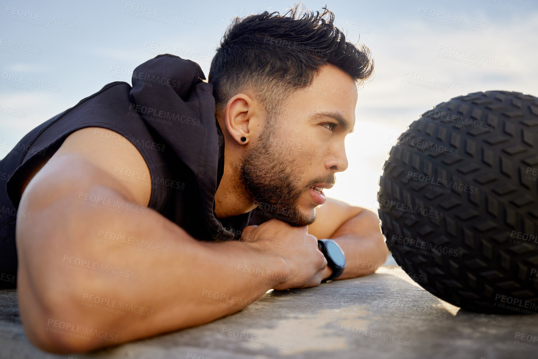 Buy stock photo Shot of a sporty young man lying outside with a medicine ball