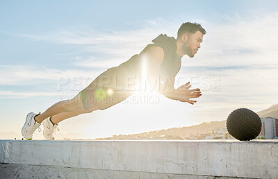 Buy stock photo Shot of a sporty young man out on a rooftop for a workout