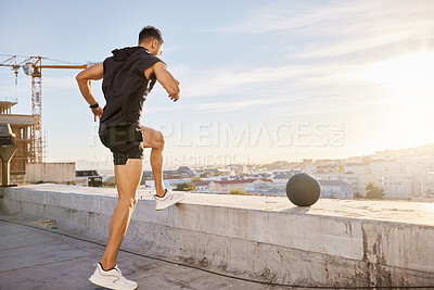 Buy stock photo Shot of a sporty young man out on a rooftop for a workout