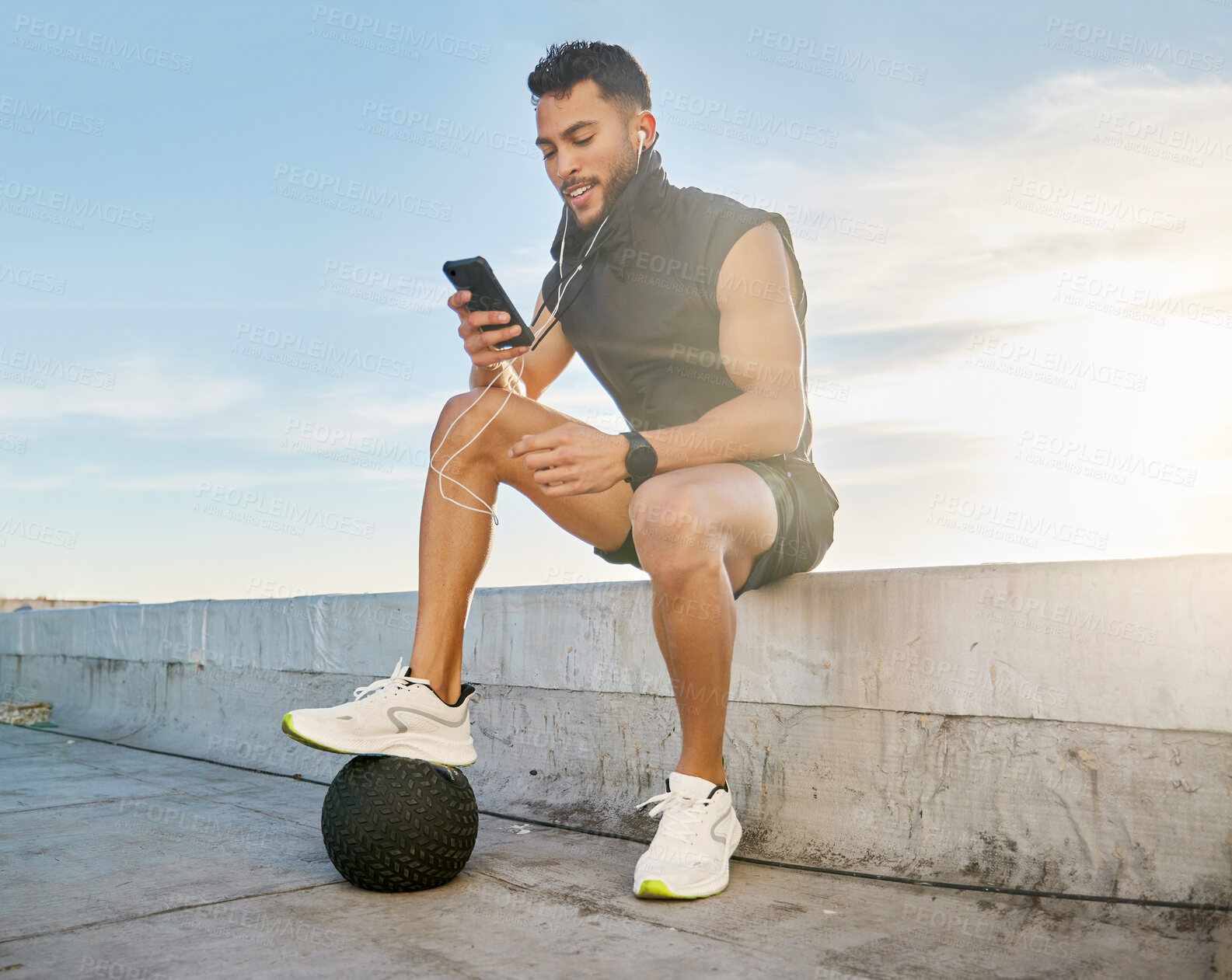 Buy stock photo Shot of a man wearing earphones while sitting outside in exercise clothes