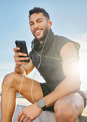 Buy stock photo Shot of a man wearing earphones while sitting outside in exercise clothes