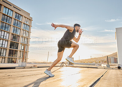 Buy stock photo Shot of a sporty young man out on a rooftop for a workout