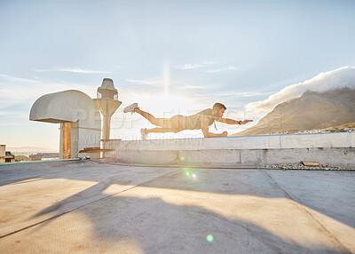 Buy stock photo Shot of a man doing a single-arm plank while on a rooftop