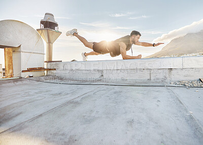 Buy stock photo Shot of a man doing a single-arm plank while on a rooftop